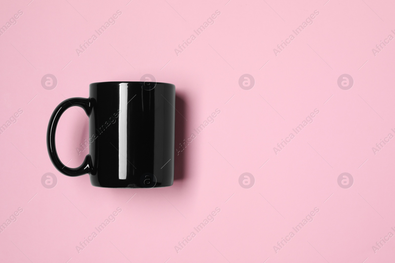 Black ceramic mug on pink background, top view. Space for text Photo of Black ceramic mug on pink background, top view. Space for text