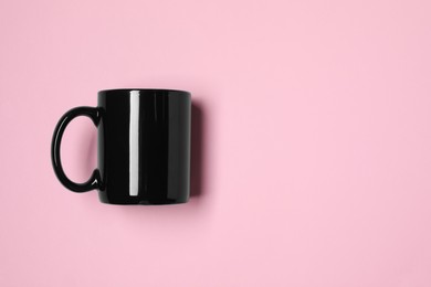 Photo of Black ceramic mug on pink background, top view. Space for text