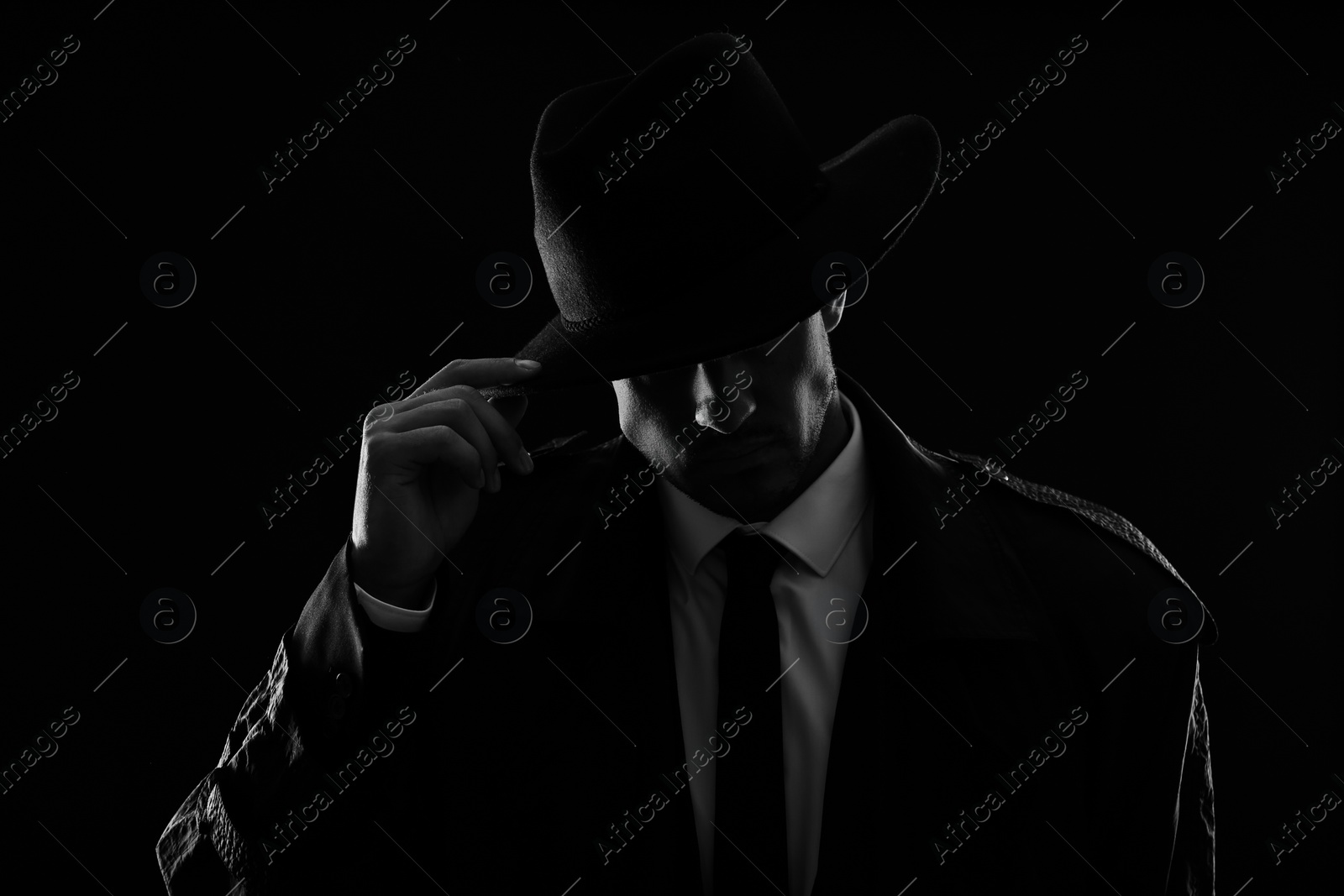 Photo of Old fashioned detective in hat on dark background, black and white effect