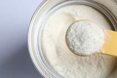 Scoop of powdered infant formula over can, top view. Baby milk