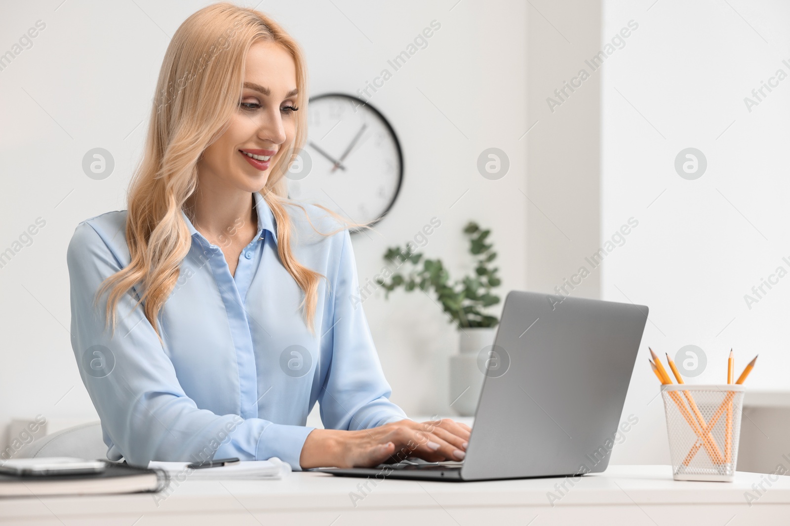 Photo of Happy secretary working with laptop in office