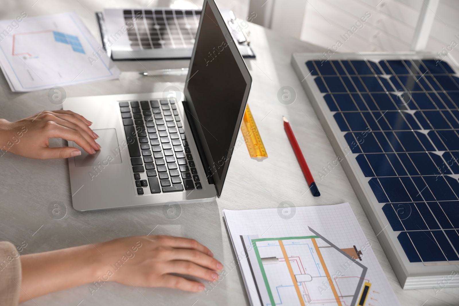 Photo of Woman working on house project with solar panels at table in office, closeup