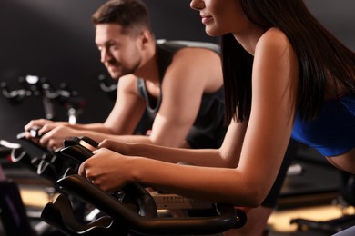 Photo of Woman and man training on exercise bikes in fitness club, closeup