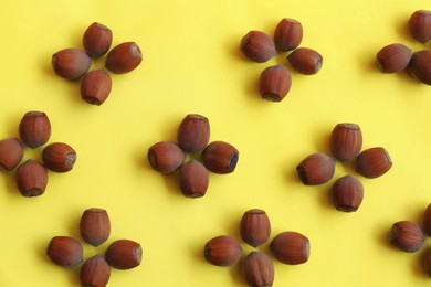 Pattern of hazelnuts on yellow background, flat lay