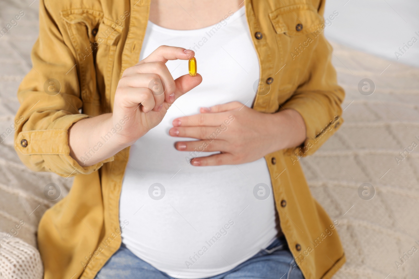 Photo of Pregnant woman taking pill on bed, closeup