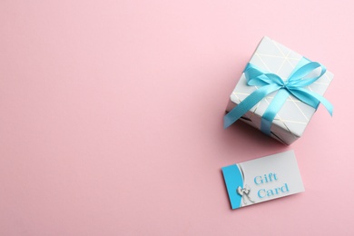Photo of Gift card and present on pink background, flat lay. Space for text