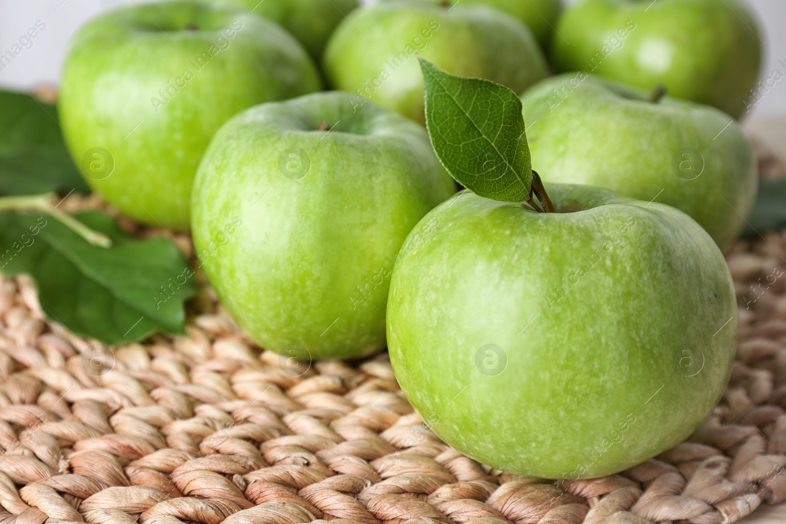 Photo of Fresh green apples on wicker mat, closeup