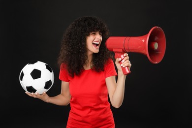 Photo of Happy fan with soccer ball using megaphone on black background