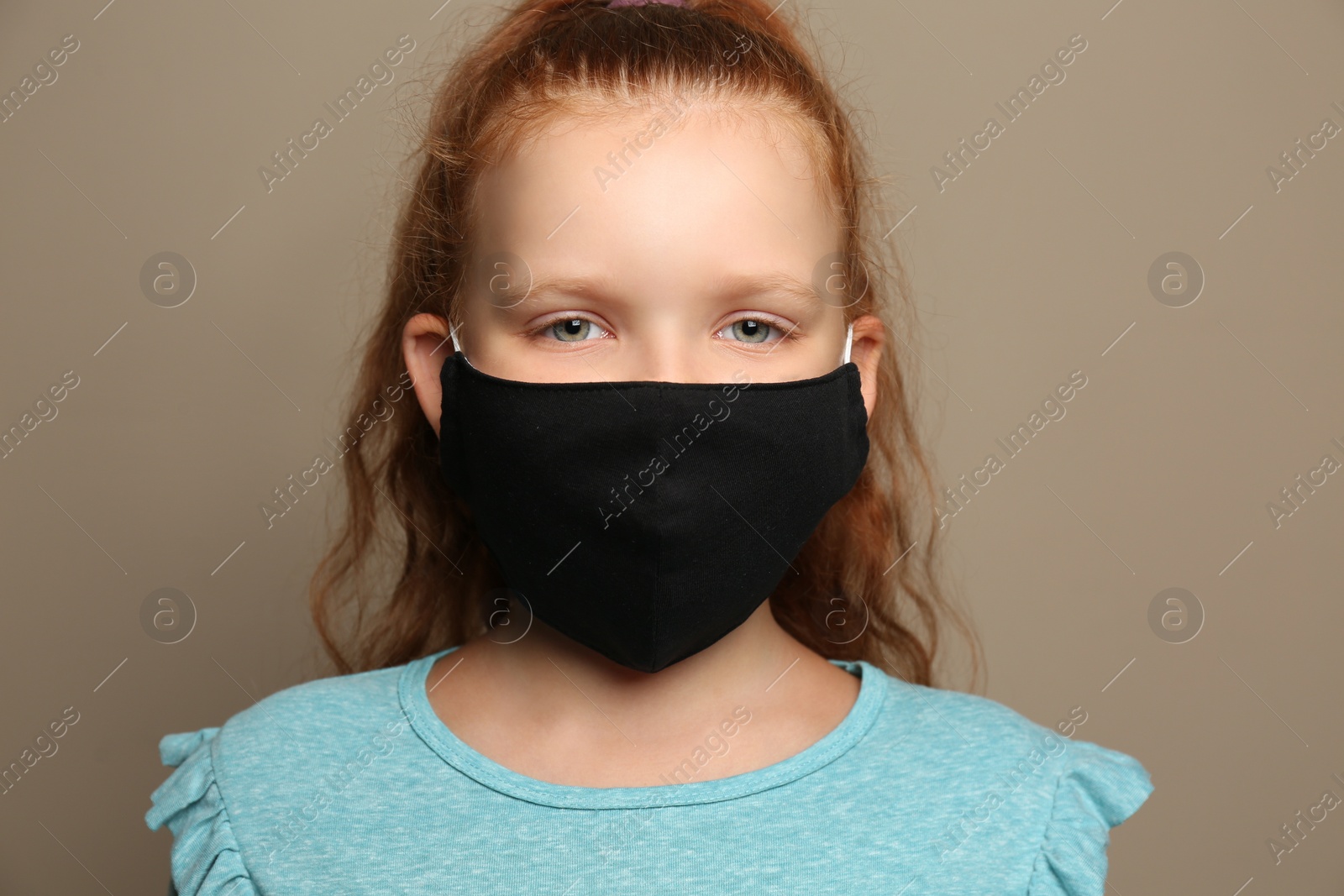 Photo of Preteen girl in protective face mask on brown background