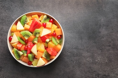 Photo of Bowl with fresh cut fruits on table, top view