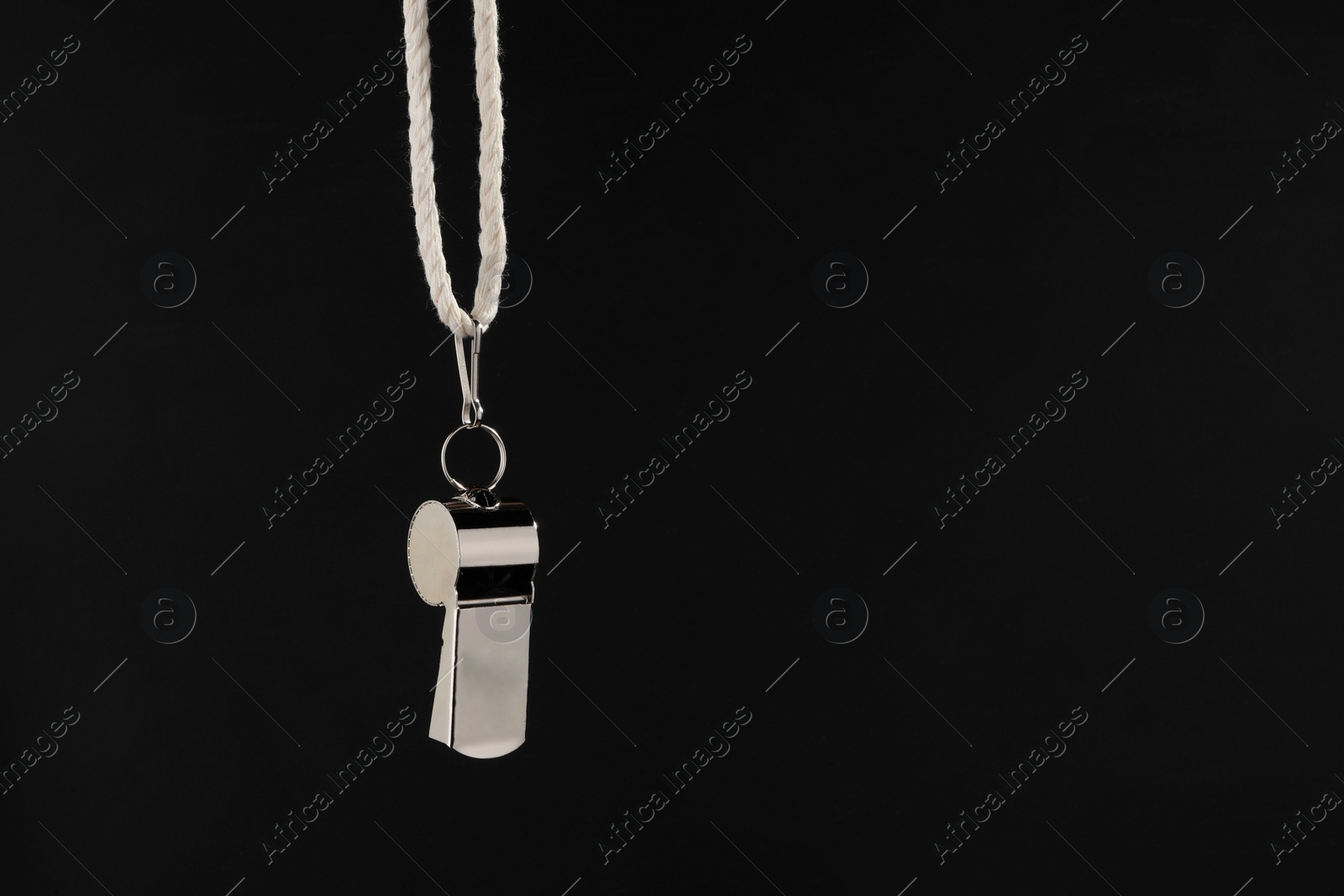 Photo of Referee equipment. Metal whistle on black background, closeup and space for text