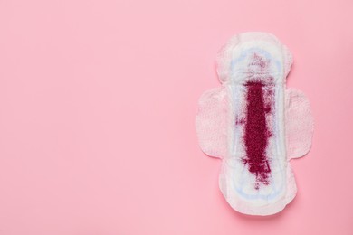 Photo of Menstrual pad with red glitter on pink background, top view. Space for text