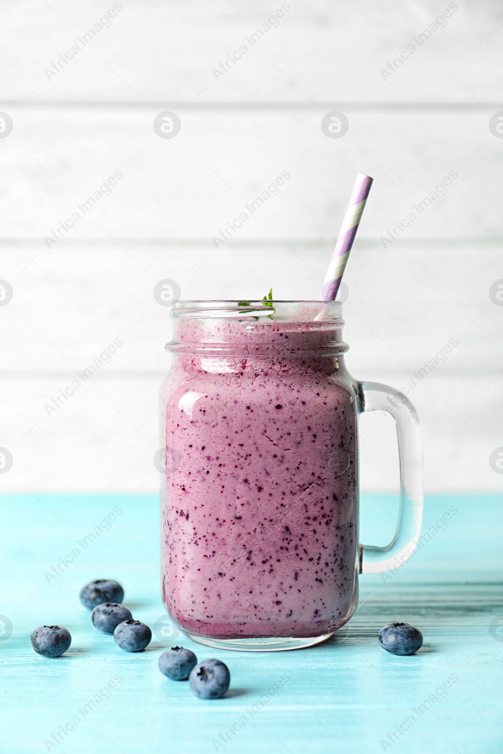 Photo of Tasty blueberry smoothie in mason jar and berries on table