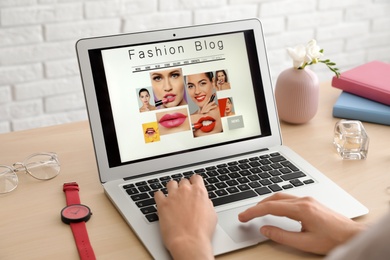 Photo of Woman working with fashion blogger site on laptop at table, closeup