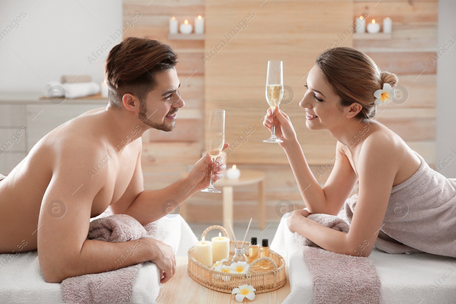 Photo of Romantic young couple with champagne in spa salon