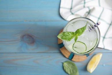 Glass of refreshing cucumber water with basil on light blue wooden table, flat lay. Space for text