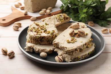 Photo of Pieces of tasty halva with pistachios on wooden table, closeup