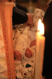 Stryi, Ukraine - September 11, 2022: Father holding child during baptism ceremony in Assumption of Blessed Virgin Mary cathedral, closeup
