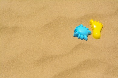 Photo of Colorful plastic molds on sand, space for text. Beach toys