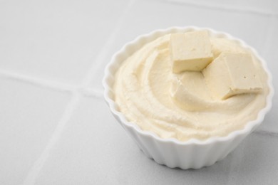 Photo of Delicious tofu sauce in bowl on white tiled table, closeup. Space for text