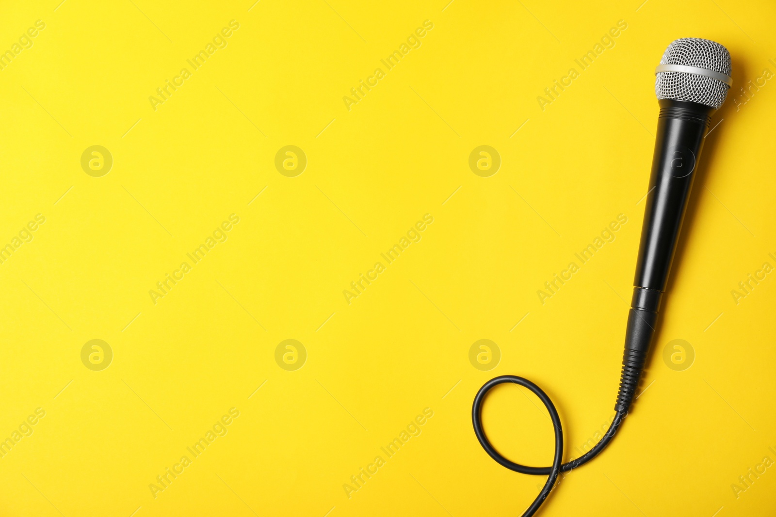 Photo of Dynamic microphone on color background, top view with space for text