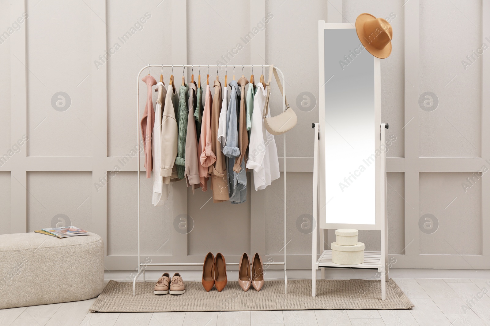 Photo of Rack with stylish women's clothes and mirror in dressing room