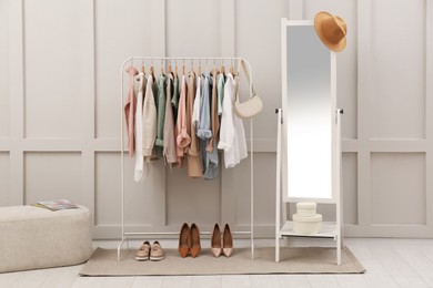 Photo of Rack with stylish women's clothes and mirror in dressing room