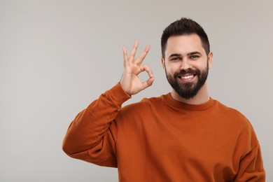 Photo of Man with clean teeth showing OK gesture on gray background, space for text