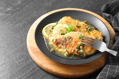 Photo of Delicious chicken piccata served on black table