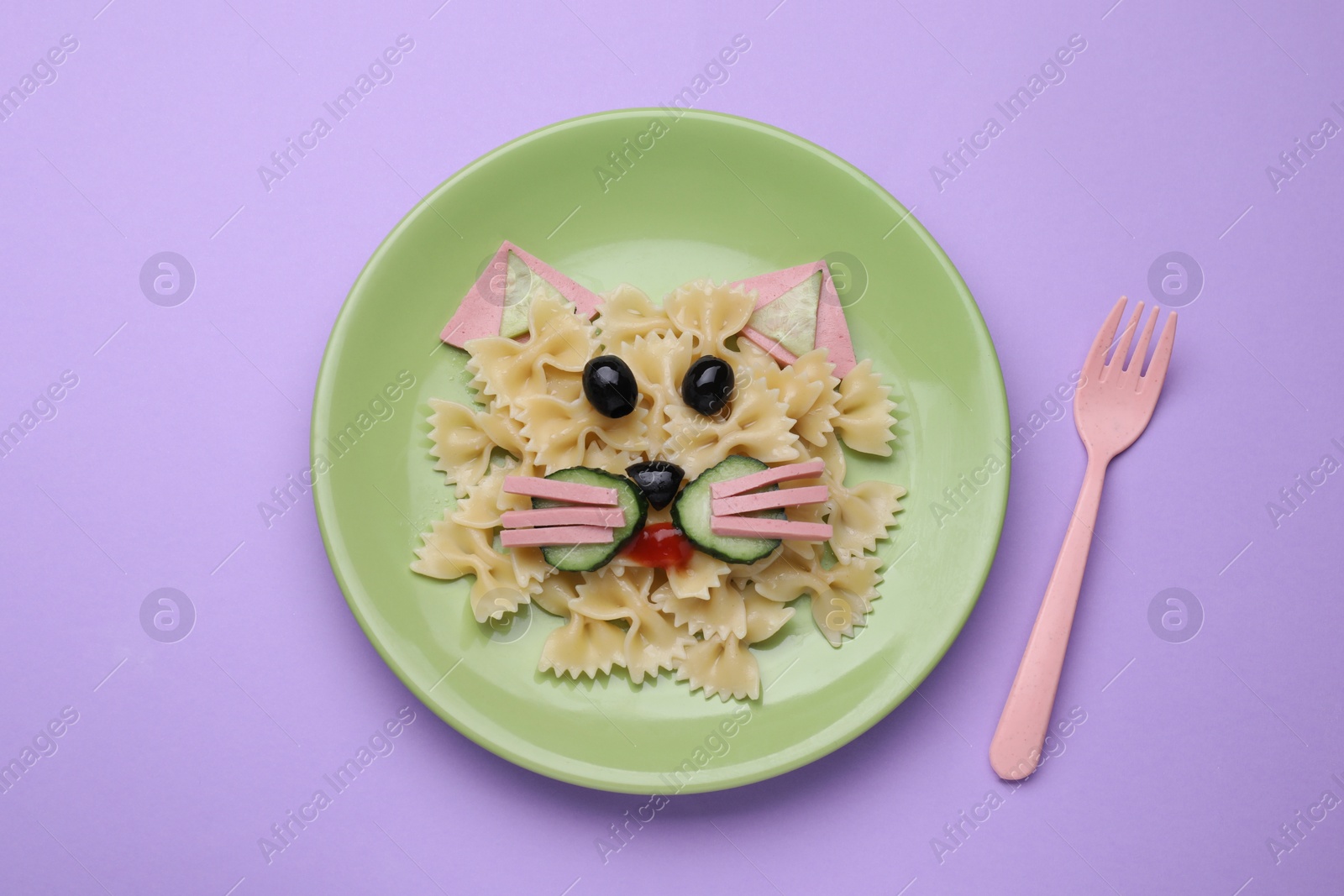 Photo of Creative serving for kids. Plate with cute cat made of tasty pasta, vegetables and sausage on violet background, flat lay