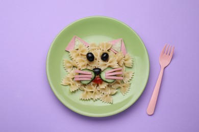 Photo of Creative serving for kids. Plate with cute cat made of tasty pasta, vegetables and sausage on violet background, flat lay