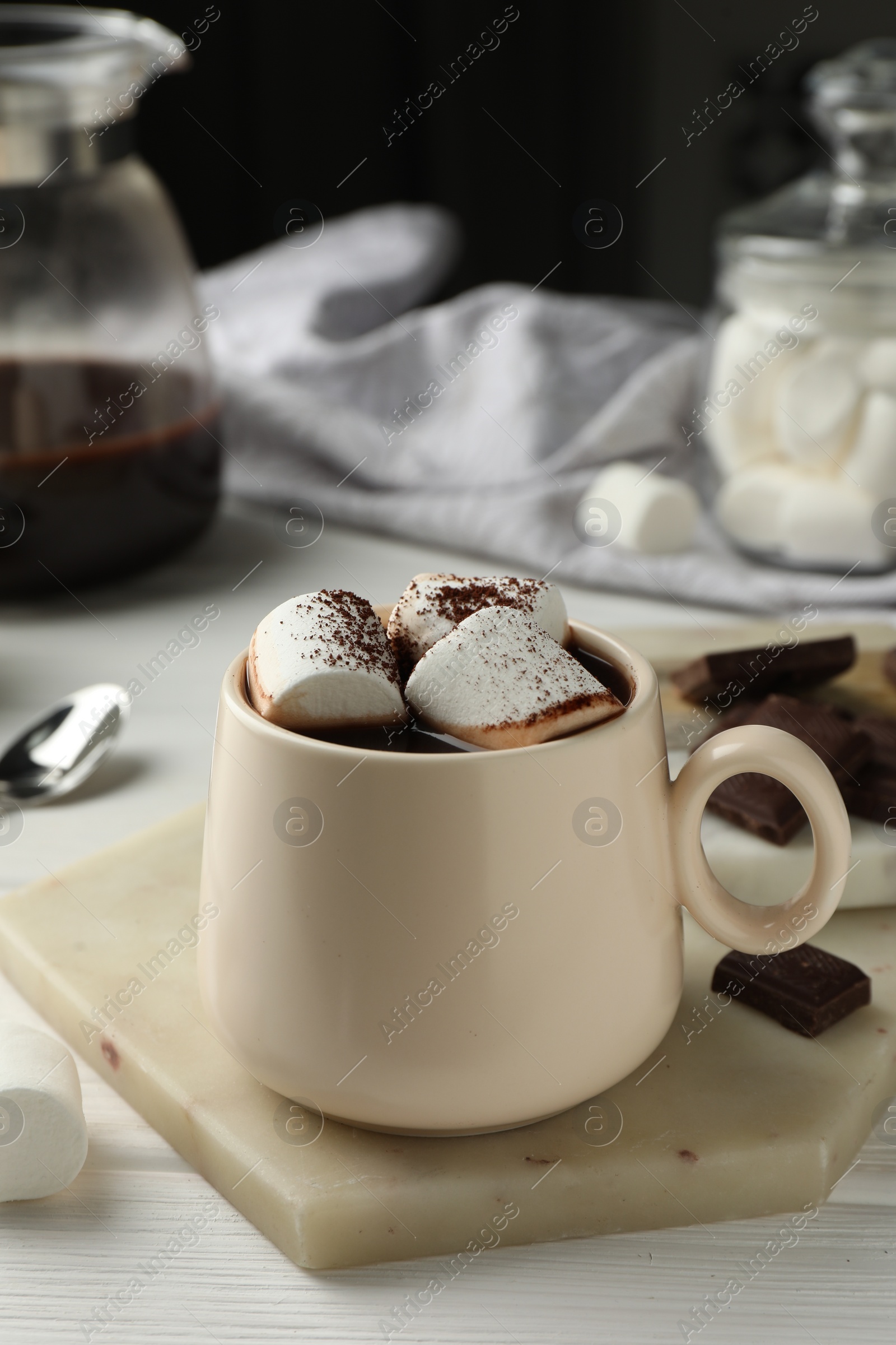 Photo of Cup of aromatic hot chocolate with marshmallows and cocoa powder on white wooden table