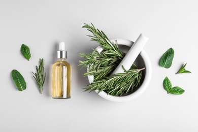 Flat lay composition with herbal essential oil on light background