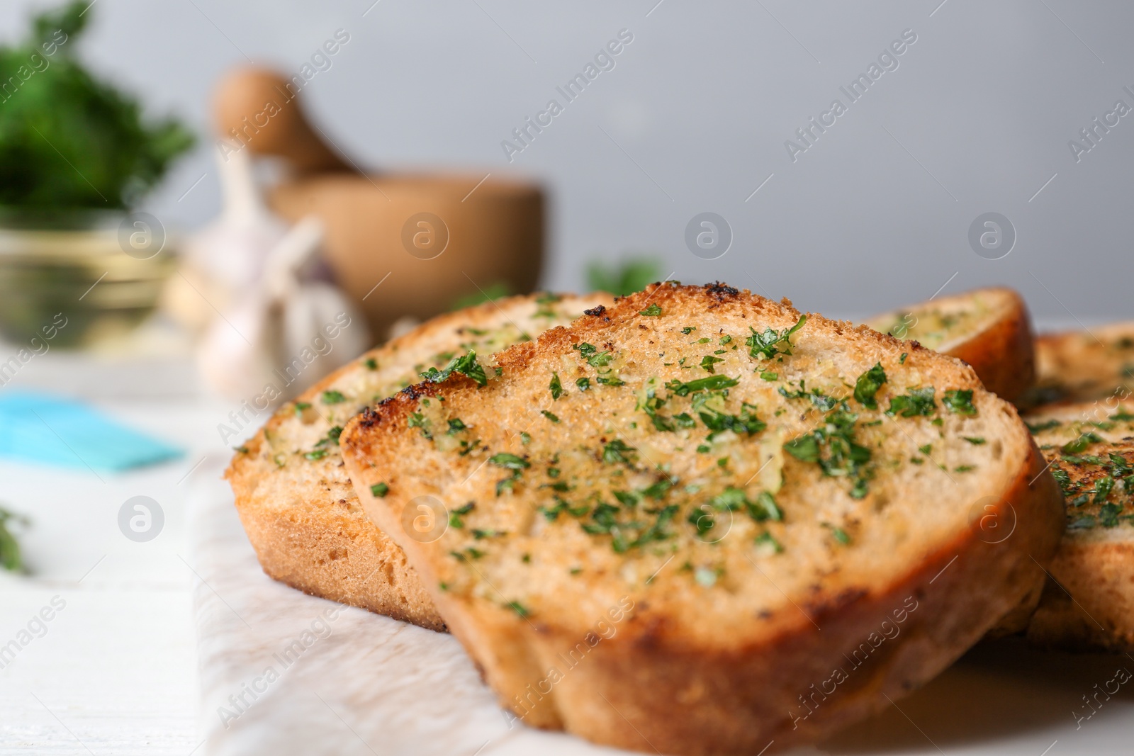 Photo of Slices of toasted bread with garlic and herbs on table, closeup