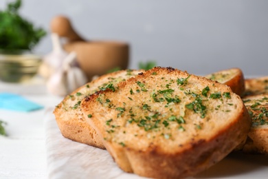 Photo of Slices of toasted bread with garlic and herbs on table, closeup