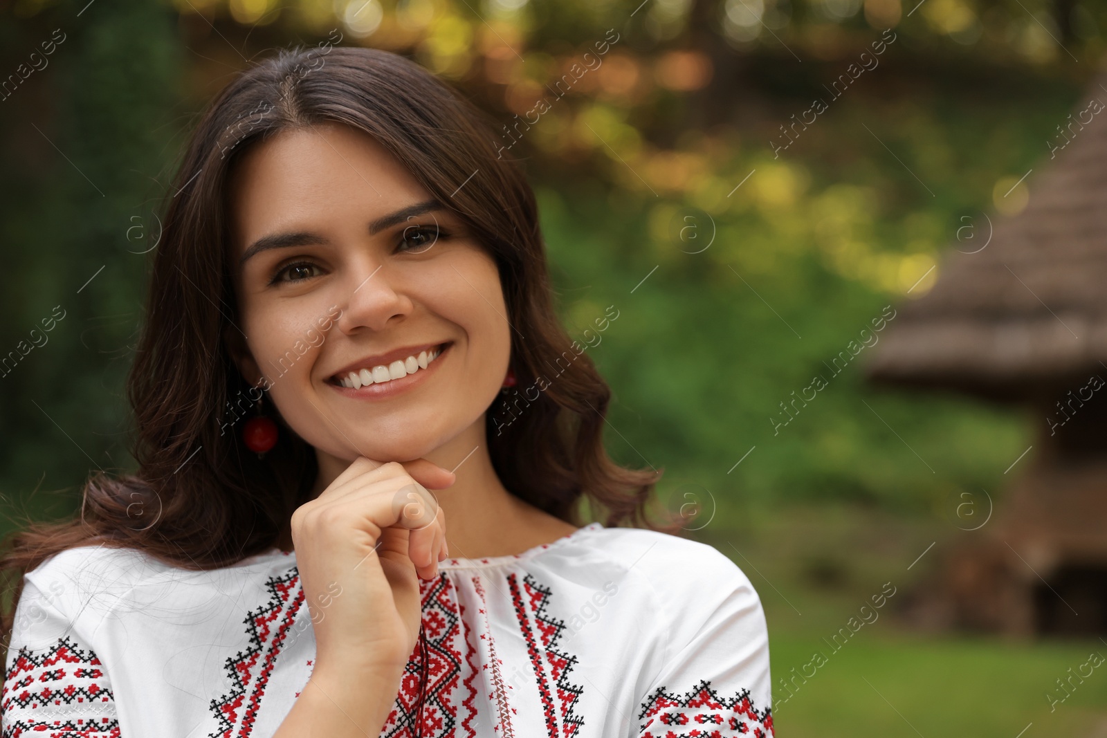 Photo of Beautiful woman wearing embroidered shirt in village, space for text. Ukrainian national clothes