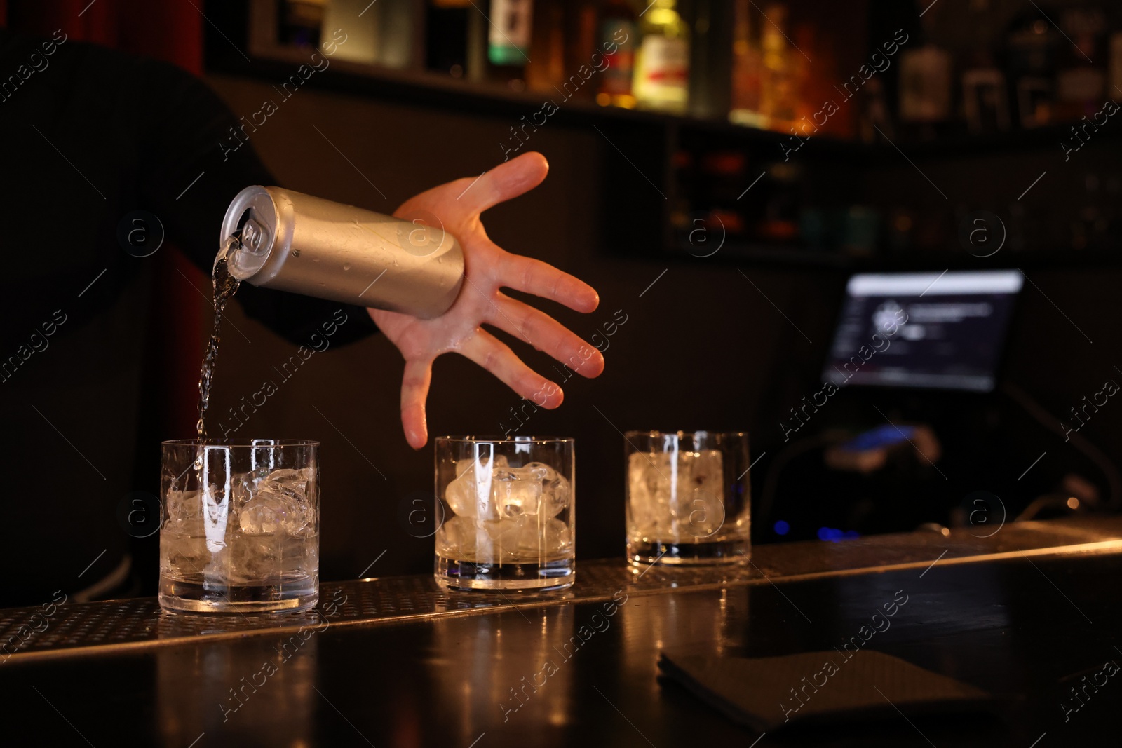 Photo of Bartender pouring energy drink into glass at counter in bar, closeup