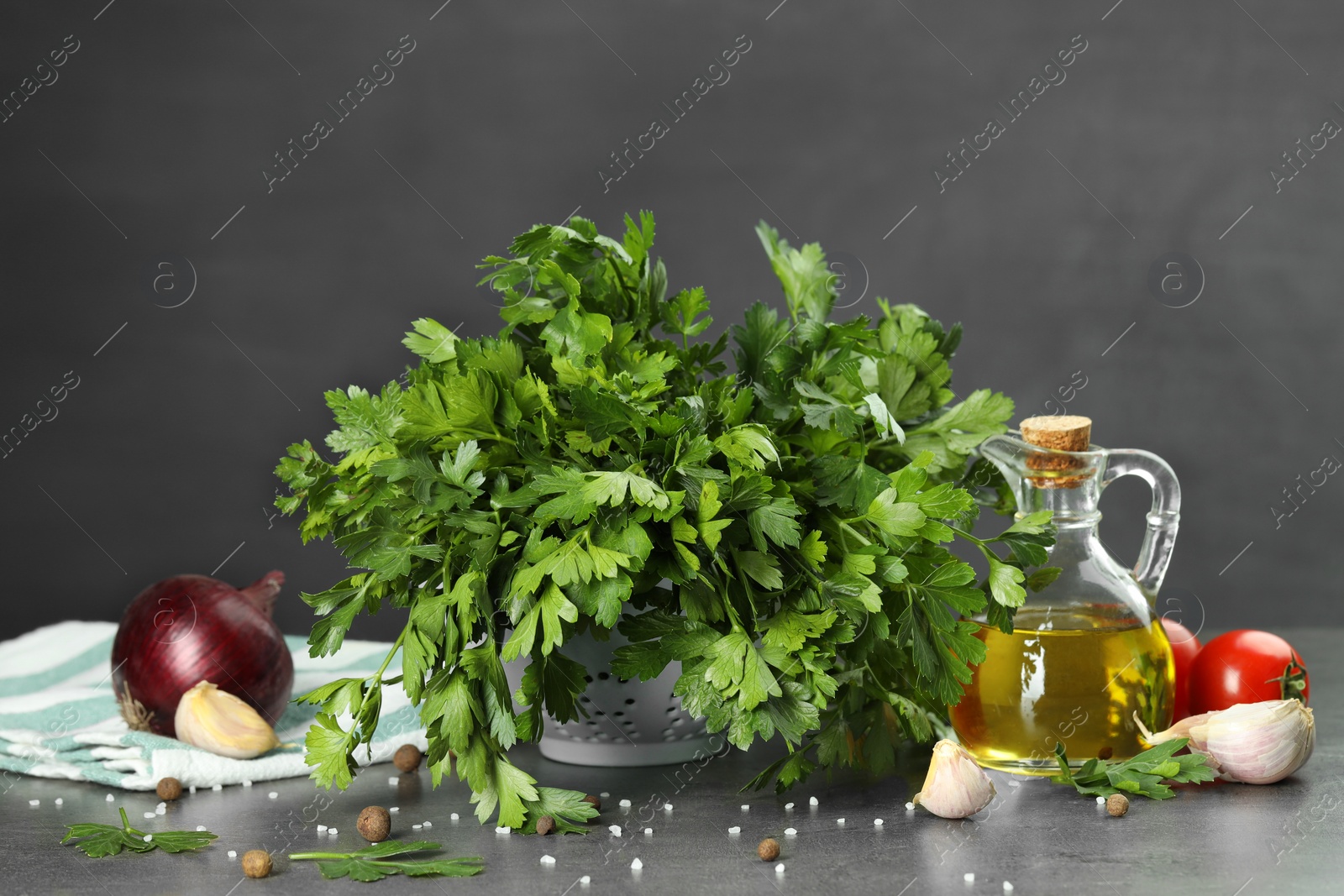 Photo of Fresh parsley, oil and other products on grey table