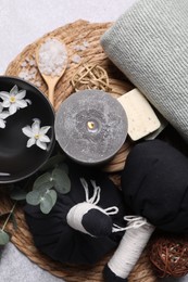 Flat lay composition with herbal massage bags, spa products and flowers on light grey table