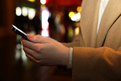 Photo of Woman with smartphone on night city street, closeup