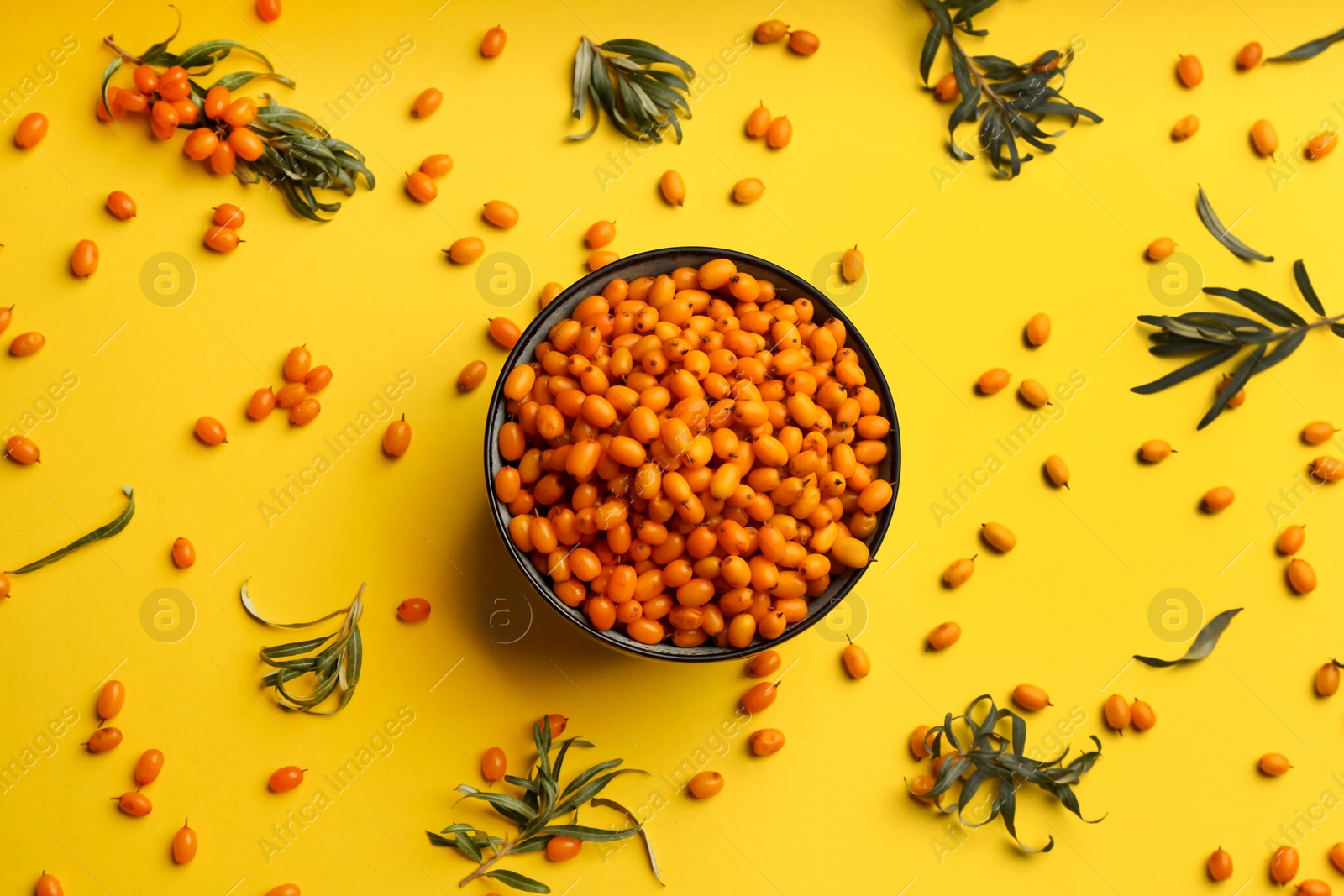 Photo of Fresh ripe sea buckthorn on yellow background, flat lay