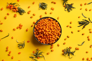 Fresh ripe sea buckthorn on yellow background, flat lay