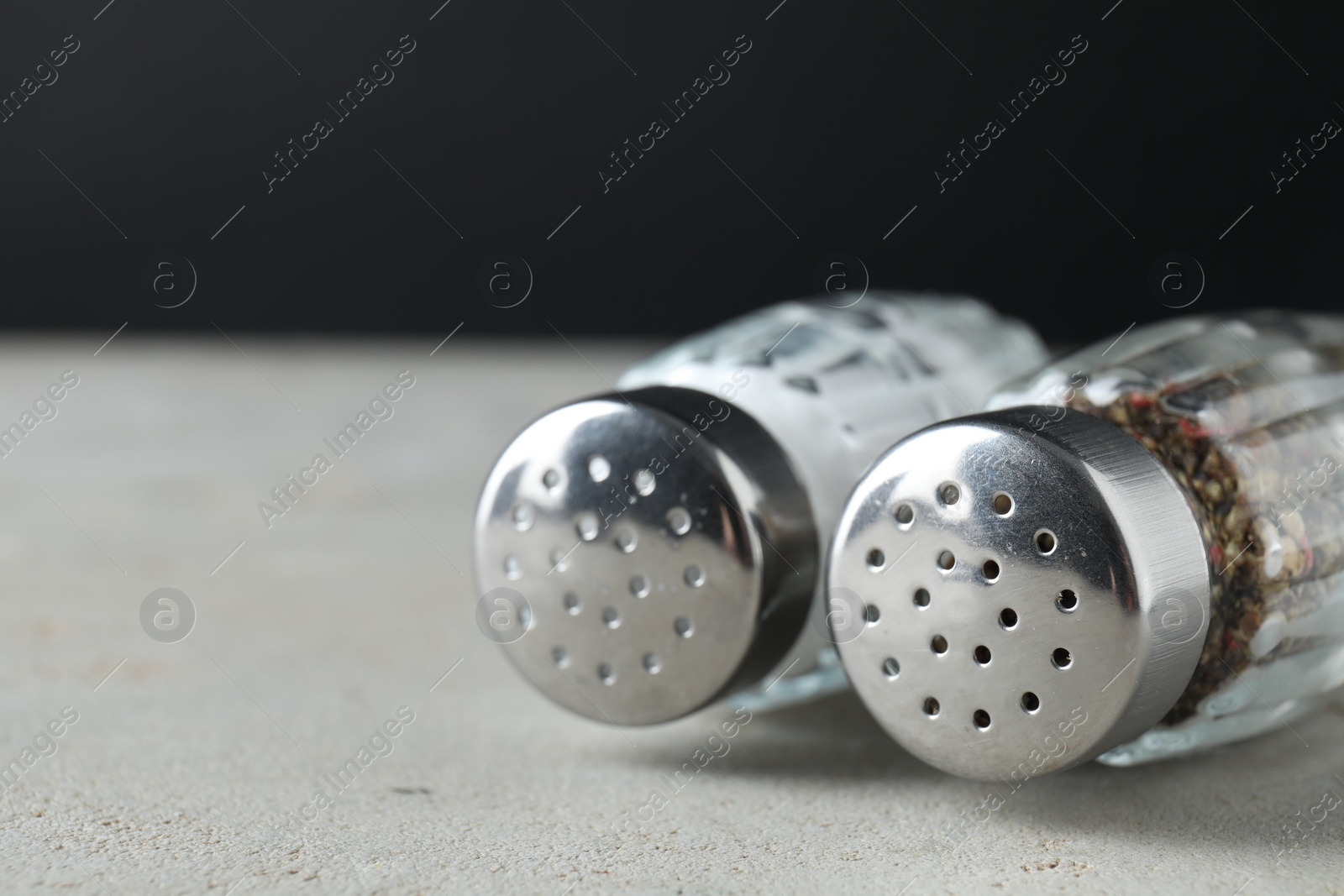 Photo of Salt and pepper shakers on light table, closeup. Space for text