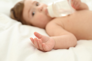 Photo of Cute little baby with bottle, focus on hand