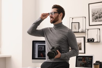 Professional photographer in glasses with digital camera in office