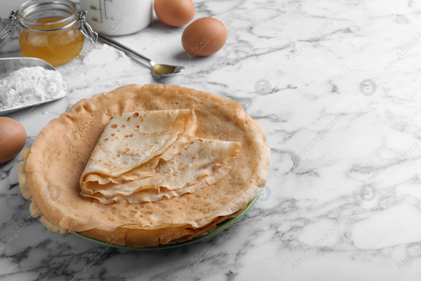 Photo of Delicious crepes and ingredients on white marble table. Space for text