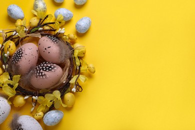 Photo of Decorative nest with many painted Easter eggs on yellow background, flat lay. Space for text