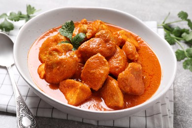 Photo of Bowl of delicious chicken curry on light grey table, closeup