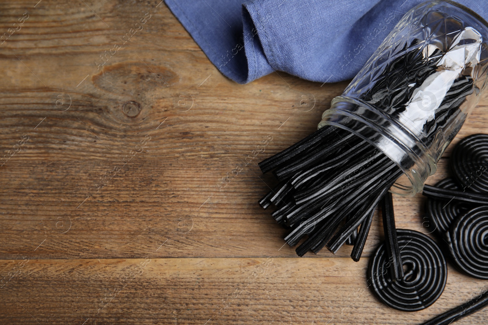 Photo of Tasty black liquorice candies on wooden table, flat lay. Space for text