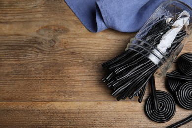 Photo of Tasty black liquorice candies on wooden table, flat lay. Space for text